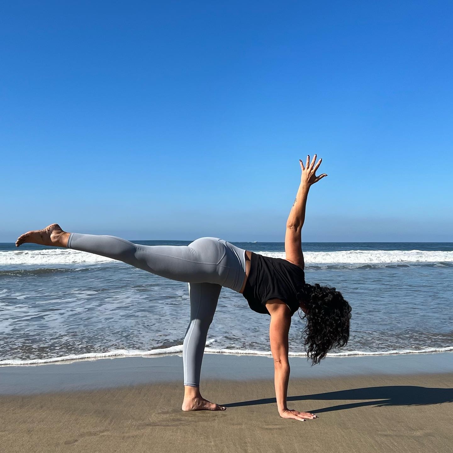 Beautiful Girl In Yoga Pose With Waves Splashing On Her On Beach